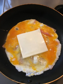 ベーコンと玉子とチーズをフライパンで焼いている